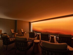 A dimly lit room with wicker chairs and a large window overlooking a sunset. - Mercure Tottori Daisen Resort & Spa (Hoki)