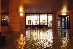 A spacious indoor area with a wooden floor and walls, large windows with framed pictures, and a door with glass panels.