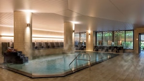 Une piscine intérieure moderne, dotée d’un espace détente avec des sièges et d’un sauna.