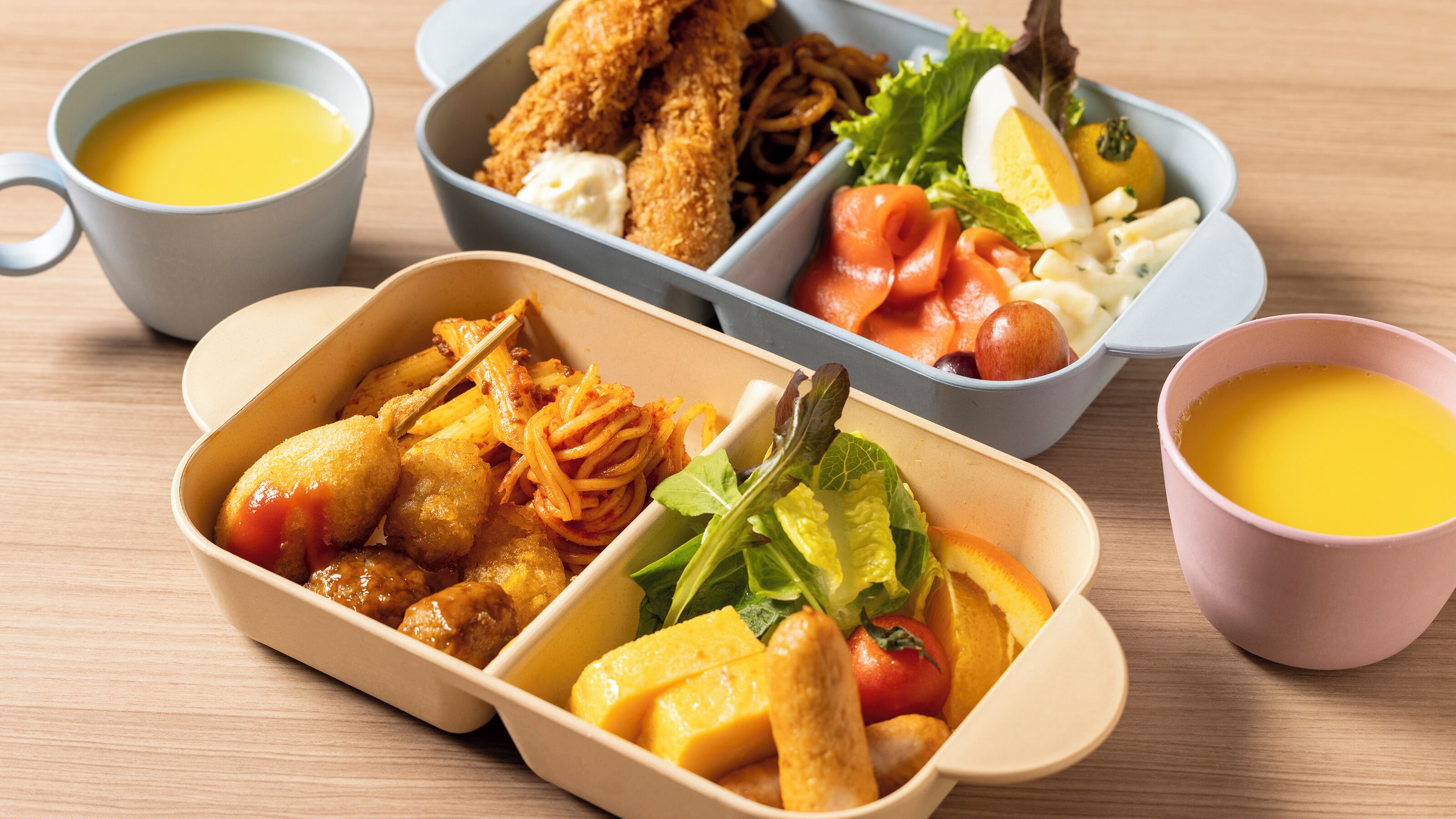 Un repas composé de différents plats, notamment des aliments frits, des légumes et une salade de fruits, servis dans des récipients variés.