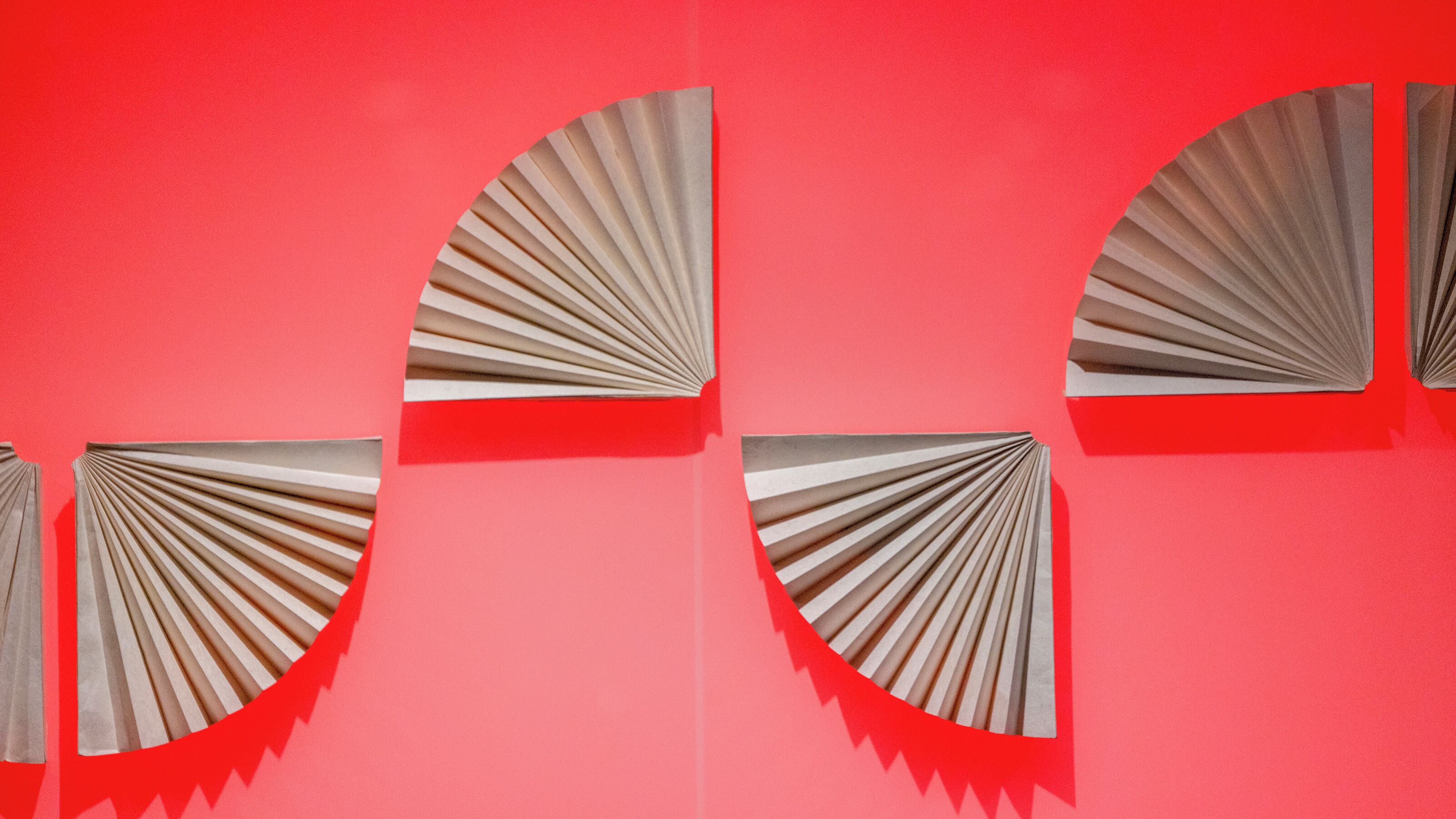 A red wall with four fan-shaped cutouts.