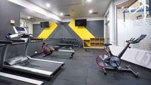 Un gimnasio con cintas de correr, bicicletas estáticas y mancuernas.