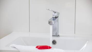 A white bathroom sink with a chrome faucet and a red soap bar.