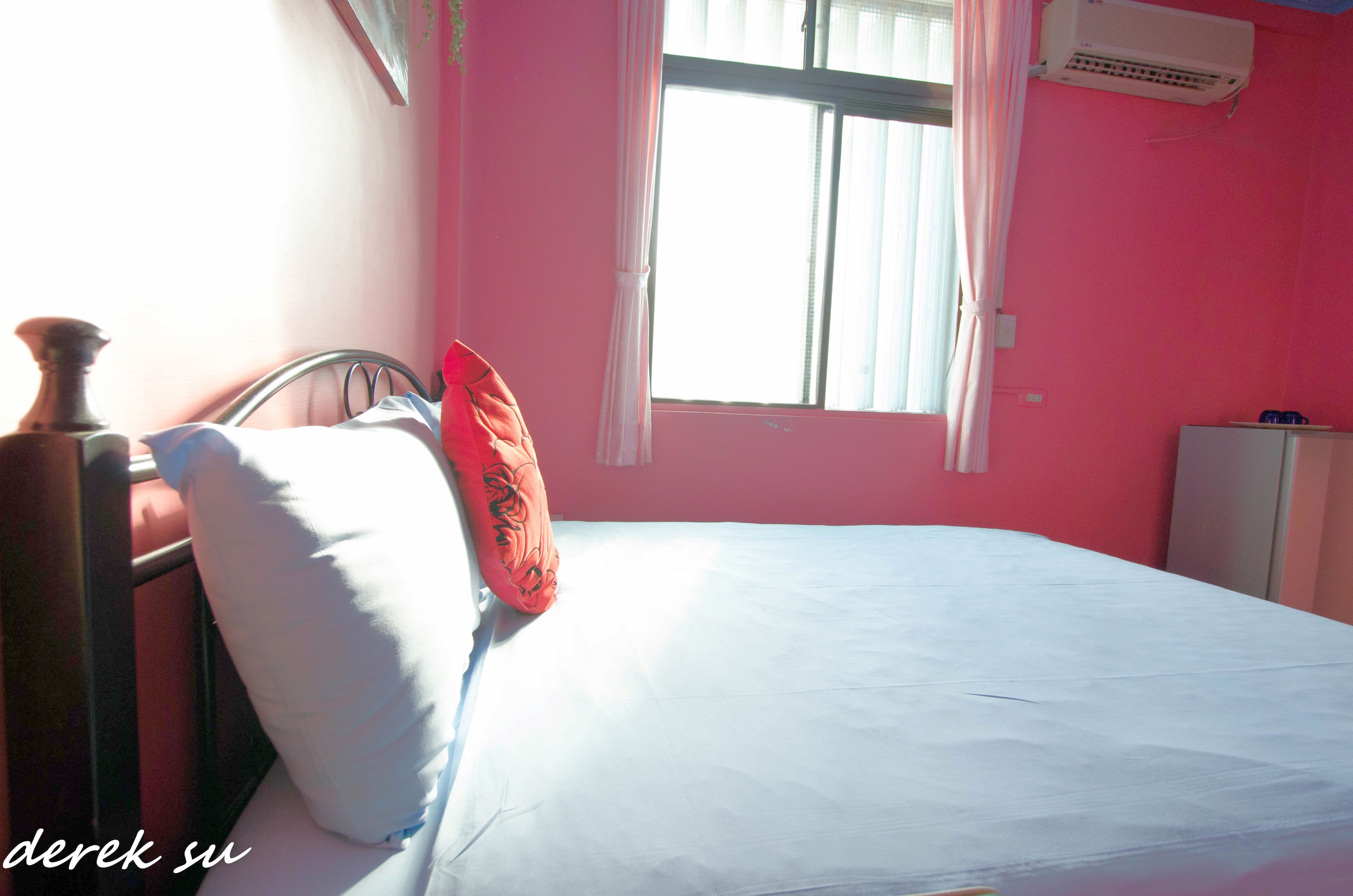 A bedroom with a bed, a pillow, a bedside table, and a window with curtains.
