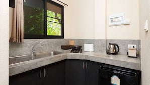 A kitchen with a sink, stove, toaster, kettle, and a dishwasher.