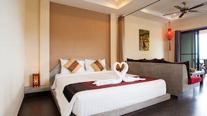 A modern hotel room with a large bed, a ceiling fan, and a view of the outdoors.