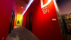 Un pasillo bien iluminado con paredes rojas y señalización que indica las duchas y los baños D5-12 y M1-16.