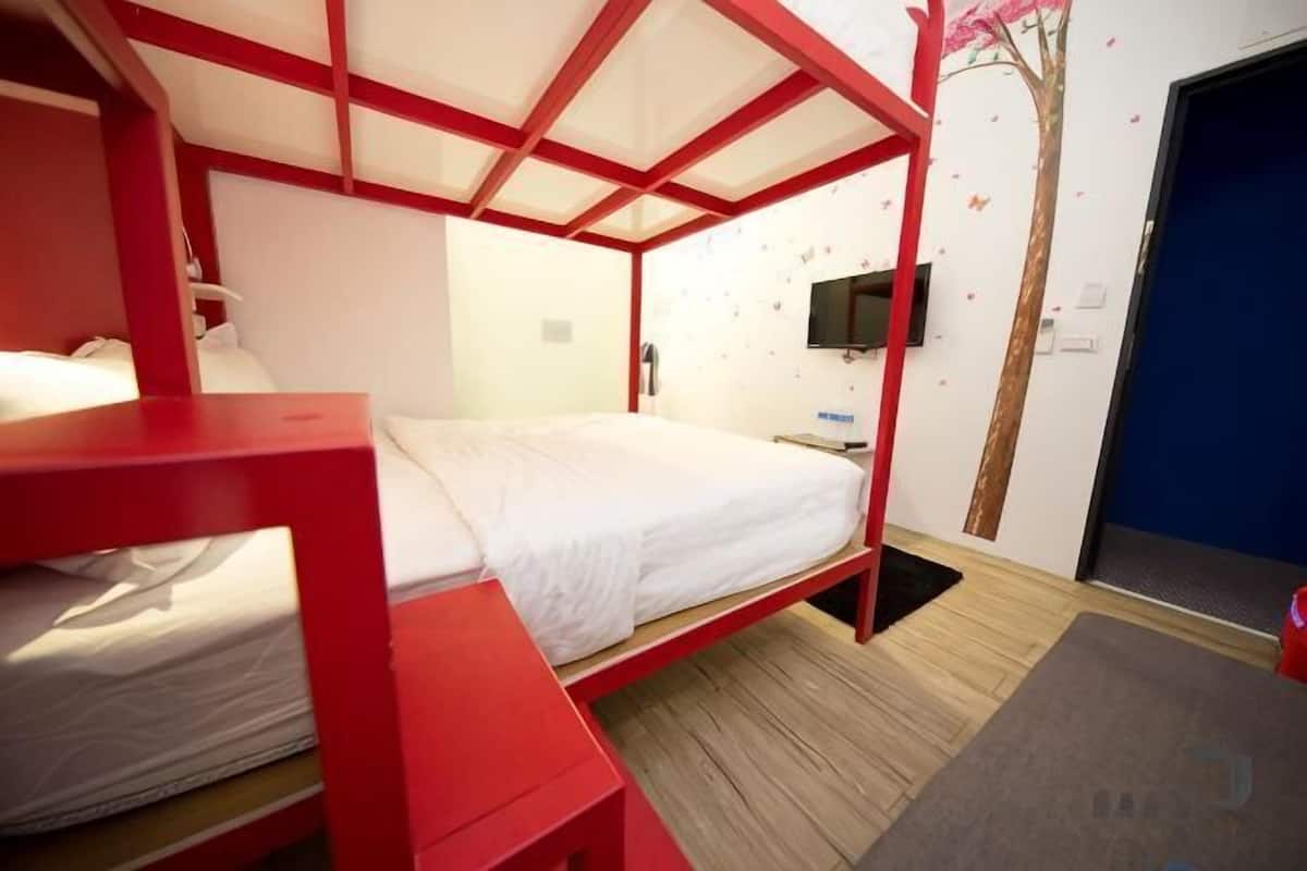 A room with bunk beds, a flat-screen TV, a wooden floor, and a tree decal on the wall.