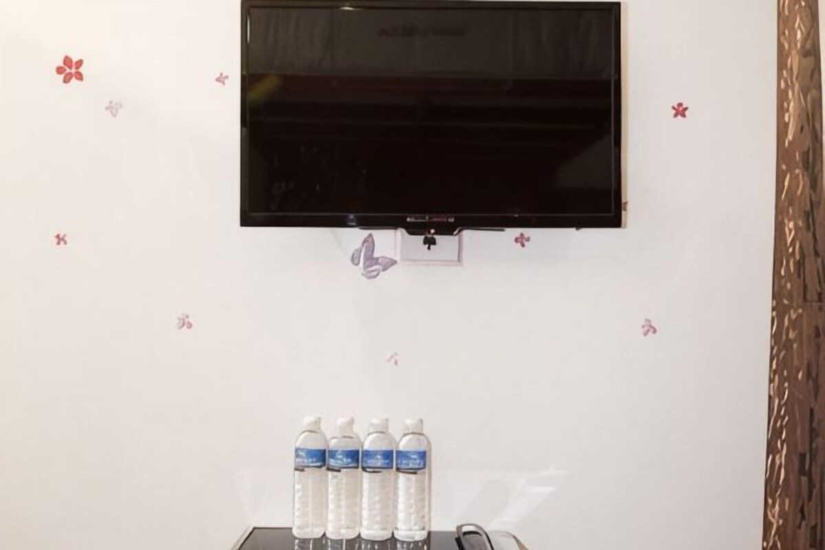 A room with a mounted TV, a water dispenser, and decorative wall stickers.