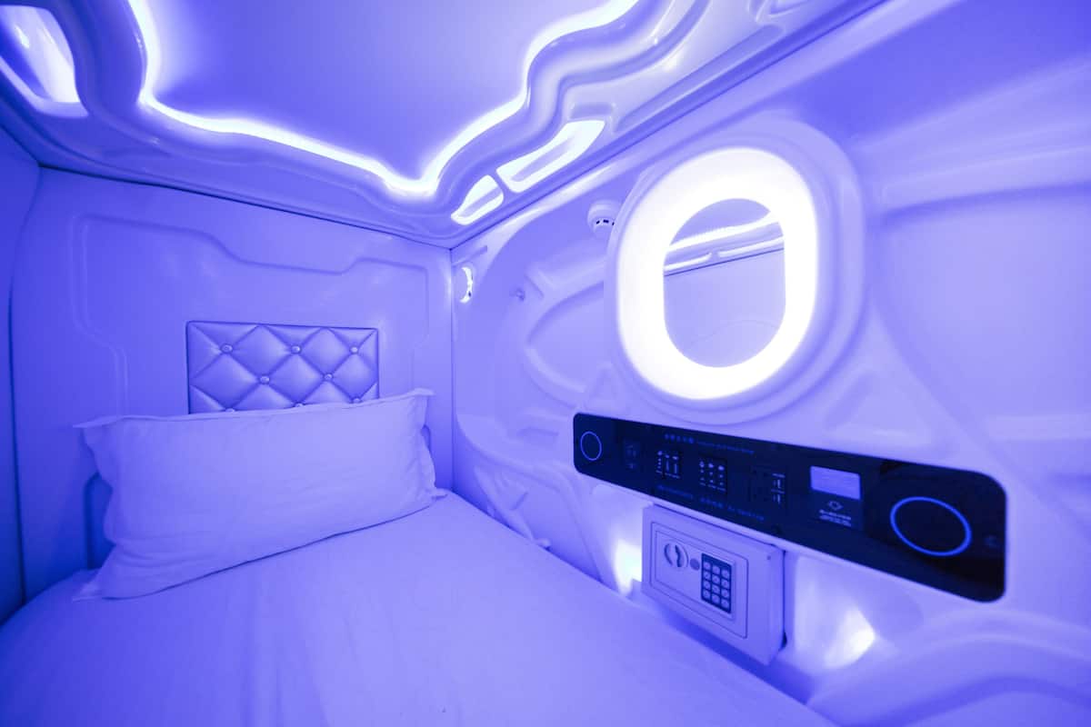 A modern room with a bed, a control panel, and a circular light fixture.