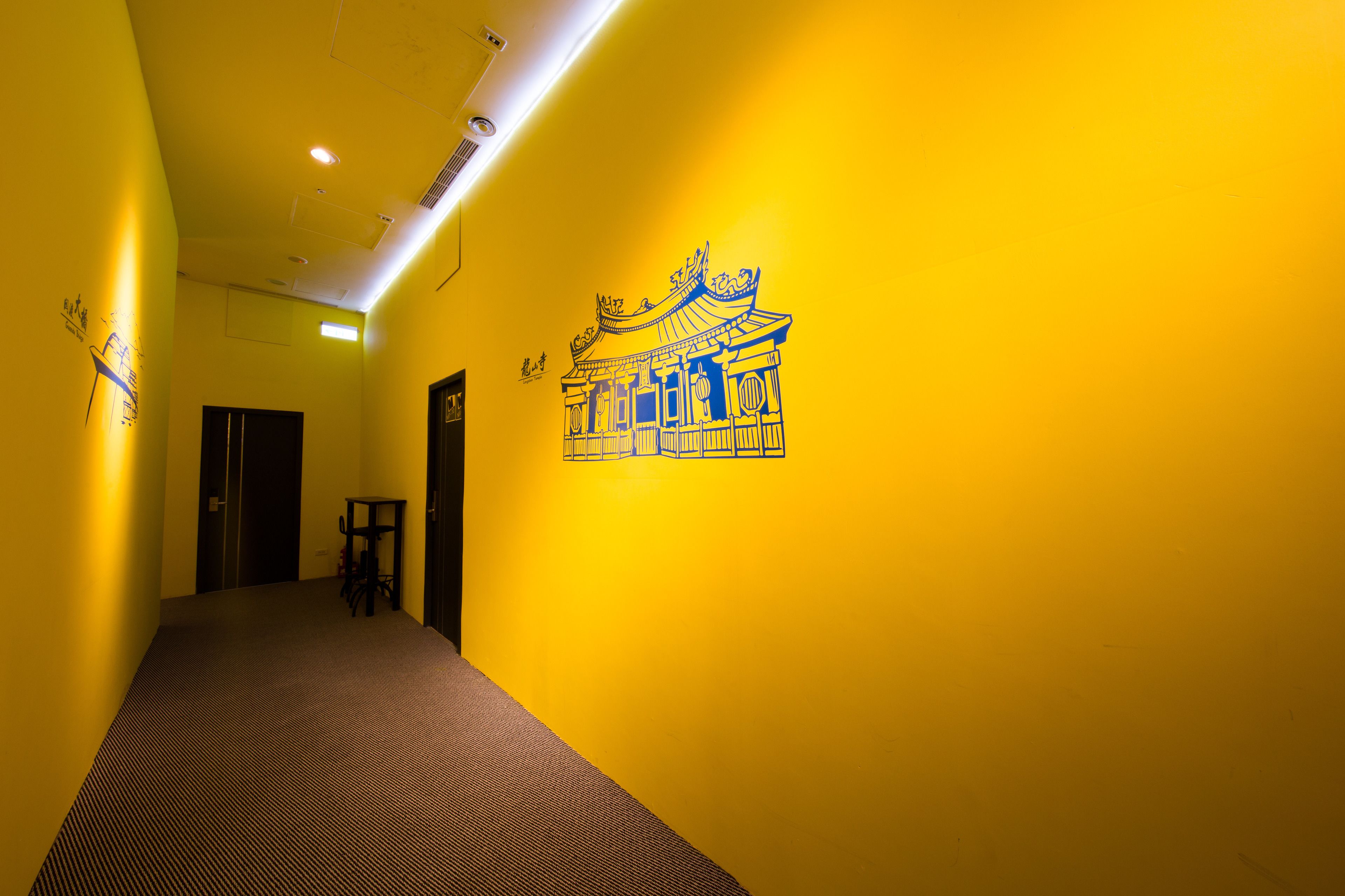 Un pasillo con paredes amarillas, alfombra estampada y un plano arquitectónico azul en la pared.