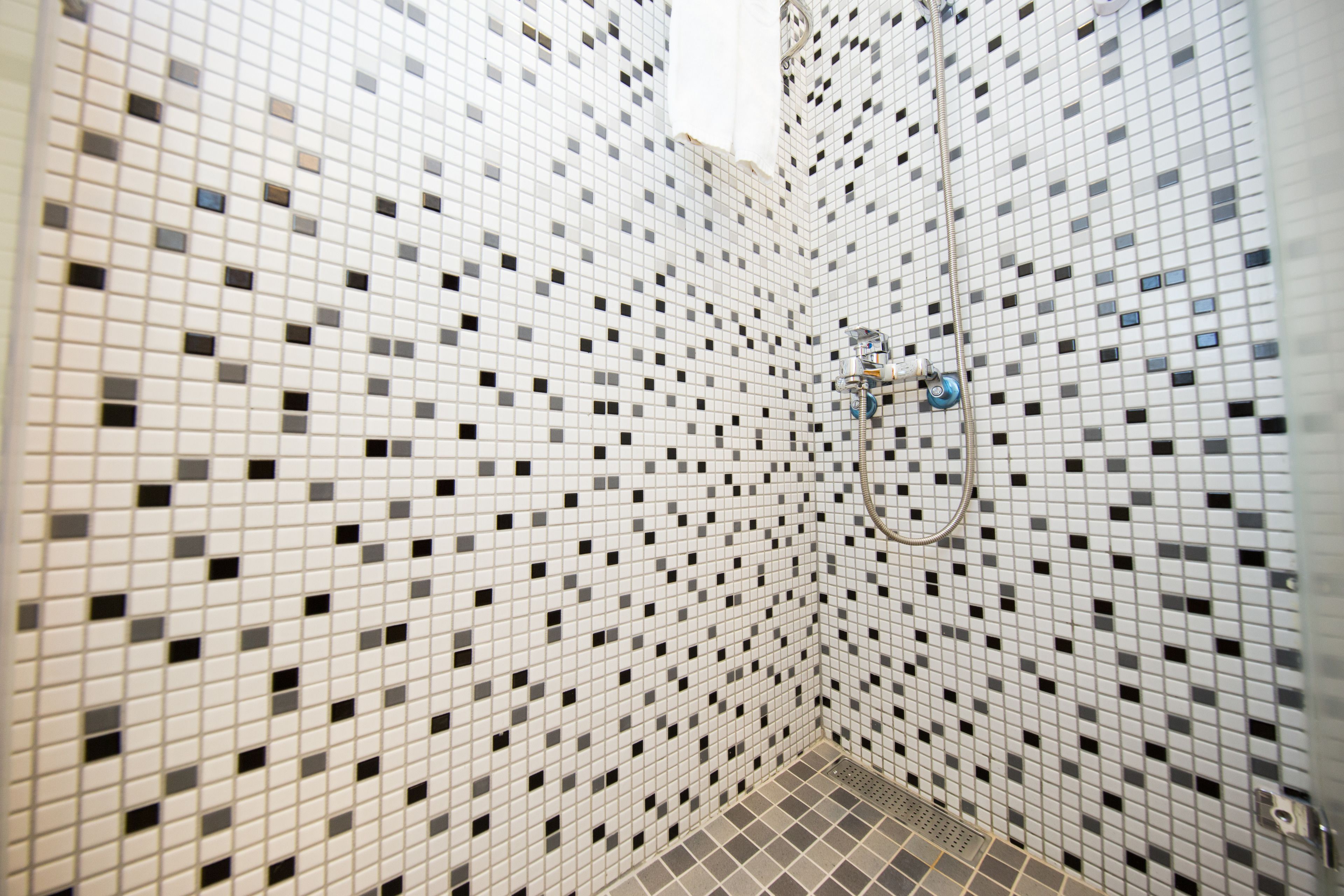 A bathroom with a tiled mosaic wall and a shower area.