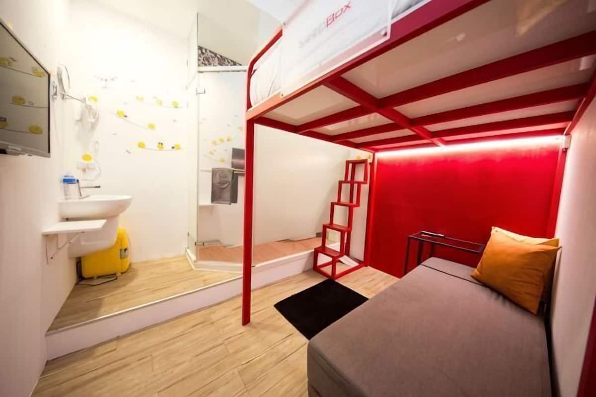 A compact room with a bunk bed, a sink, and a small ladder.
