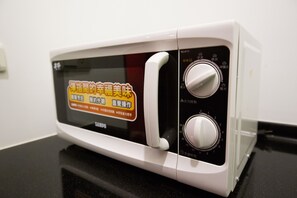 A white microwave oven with a digital display and two control knobs. - SleepBox Hotel - Ximen (Taipei)