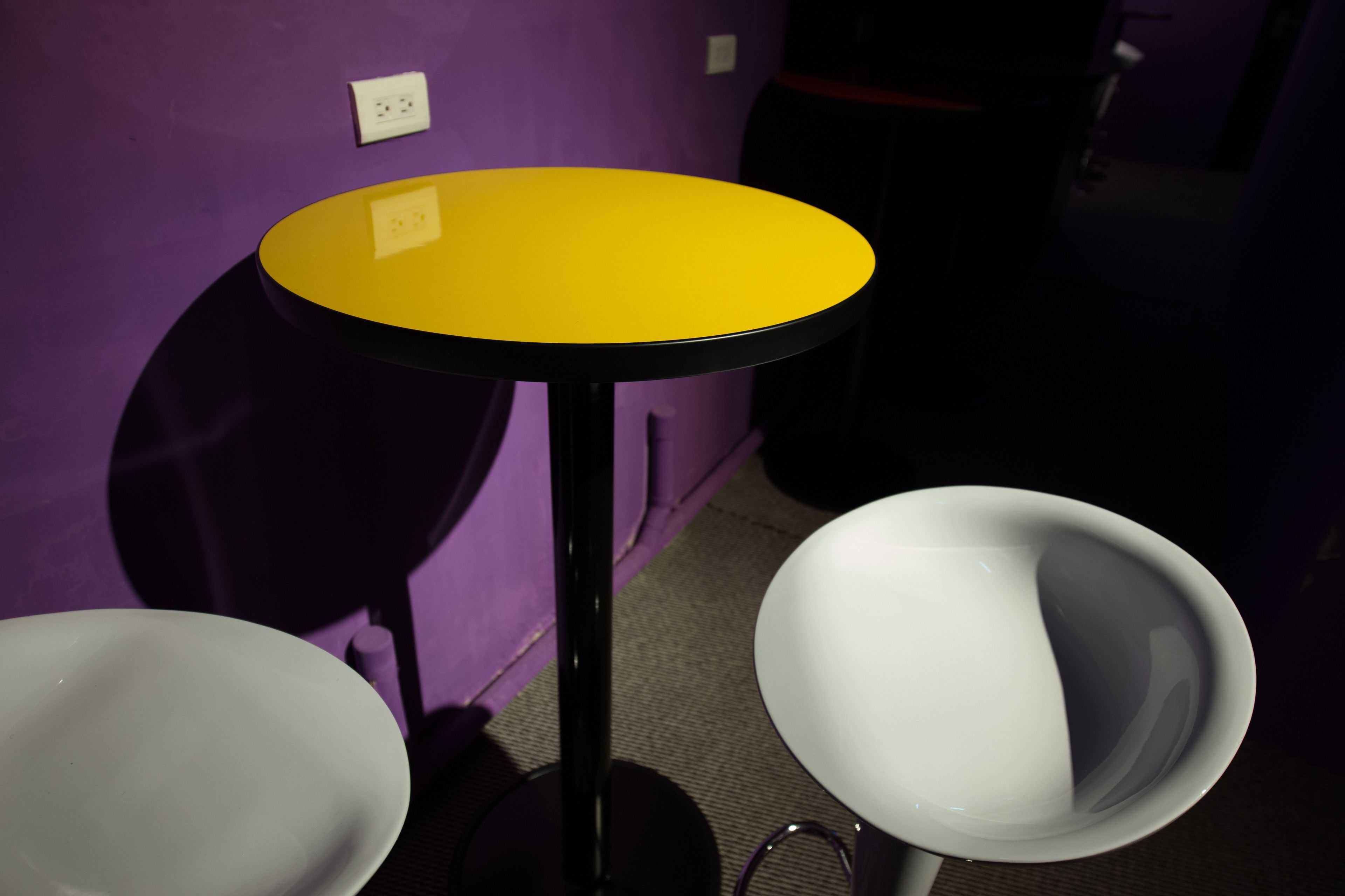 A small room with a yellow table, two white chairs, and purple walls.