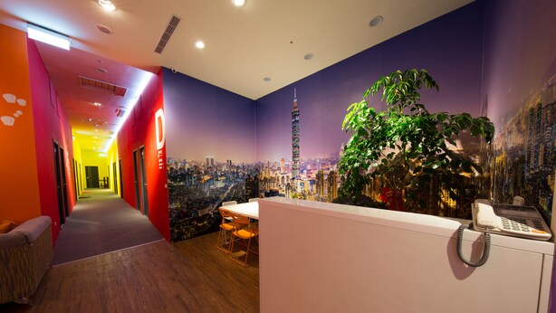 Vestíbulo de hotel con un mural de la ciudad, una recepción y un comedor con sillas.