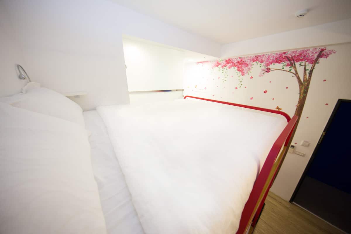 A bedroom with a single bed, a white wall, and a door.