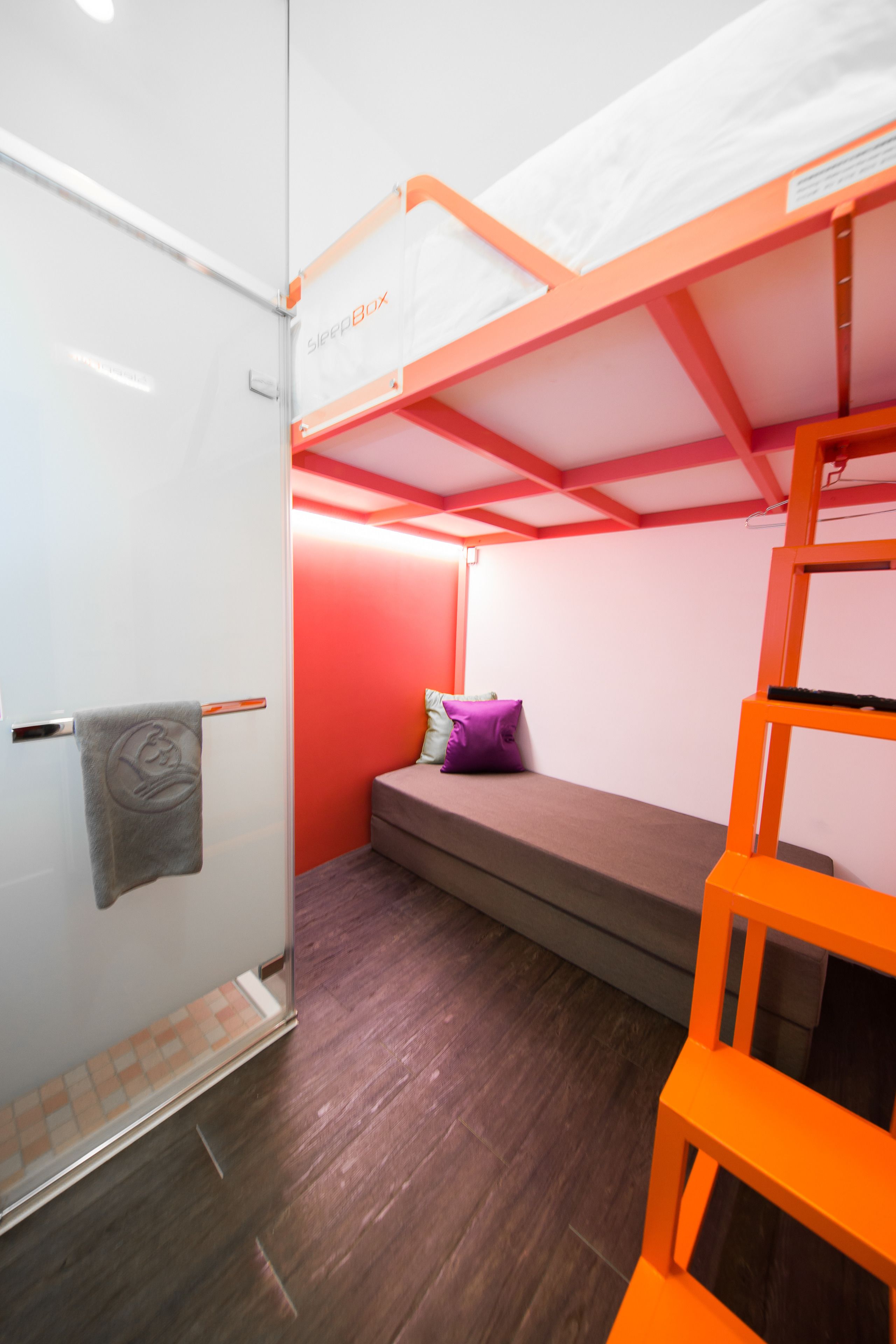 A compact room with a bunk bed, a small seating area, and a ladder.