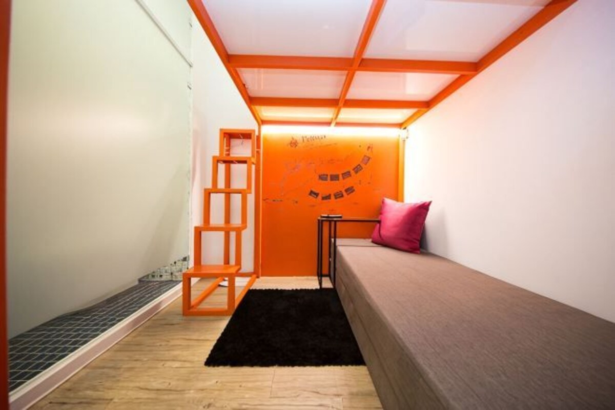 A small room with a bunk bed, a ladder, a small table, and a wall with a mural.