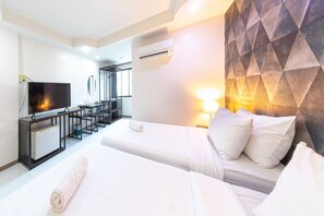 Habitación de hotel con dos camas, televisor, escritorio y un moderno diseño de pared geométrico.