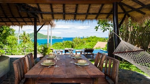 A wooden dining table set for six with plates, glasses, and cutlery, overlooking a pool and lush greenery. - Koh Tao Heights Boutique Villas (Koh Tao)