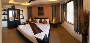 A well-lit bedroom with a large bed, bedside lamps, a Buddha painting, and a window with curtains. - Koh Tao Heights Boutique Villas (Koh Tao)