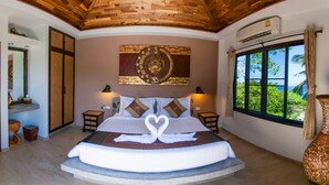 A spacious bedroom with a curved ceiling, a large bed with a swan-shaped pillow arrangement, a wall-mounted air conditioning unit, and a window offering a view of greenery. - Koh Tao Heights Pool Villas (Koh Tao)