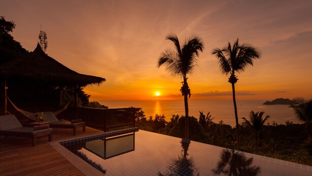 A sunset view from a poolside area with lounge chairs and a thatched-roof structure. - Koh Tao Heights Pool Villas (Koh Tao)