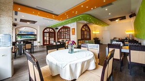 A restaurant with a round table, chairs, and a vase of flowers. - Penghu Royal (Magong)