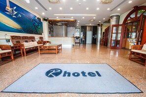 A hotel lobby with a reception desk, seating area, and a large mural on the wall.