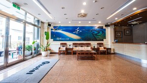 A hotel lobby with a large ocean mural, seating area, and a reception desk. - Penghu Royal (Magong)