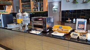 A breakfast buffet area with a self-serve coffee machine, a bread display, and a sign advertising a $12 breakfast.