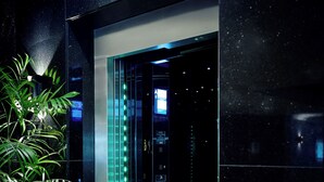 An elevator with a glass door, illuminated by green lights, and a digital display. - Great Southern Hotel Perth (Perth)