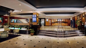 A hotel lobby with a reception desk, seating area, and a staircase leading to the upper floors. - Great Southern Hotel Perth (Perth)