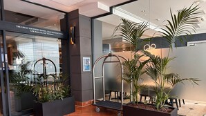A hotel lobby with a modern design, featuring a reception desk, potted plants, and a glass entrance. - Great Southern Hotel Perth (Perth)