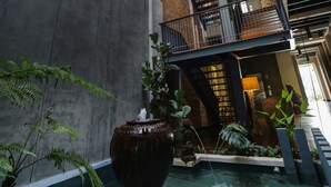 A multi-level atrium with a central water feature, stone walls, and a wooden ceiling.