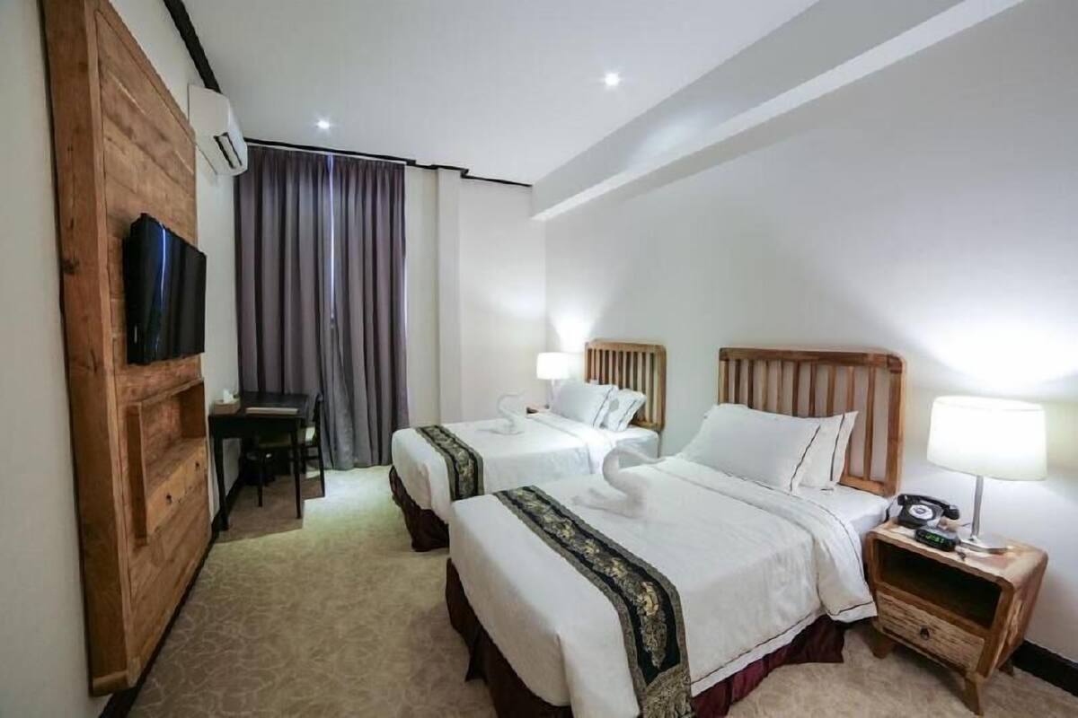 Une chambre d’hôtel avec deux lits, une télévision, un bureau et une chaise.