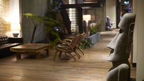 A cozy lounge area with wooden flooring, a stone statue, and a seating arrangement including a sofa and chairs.