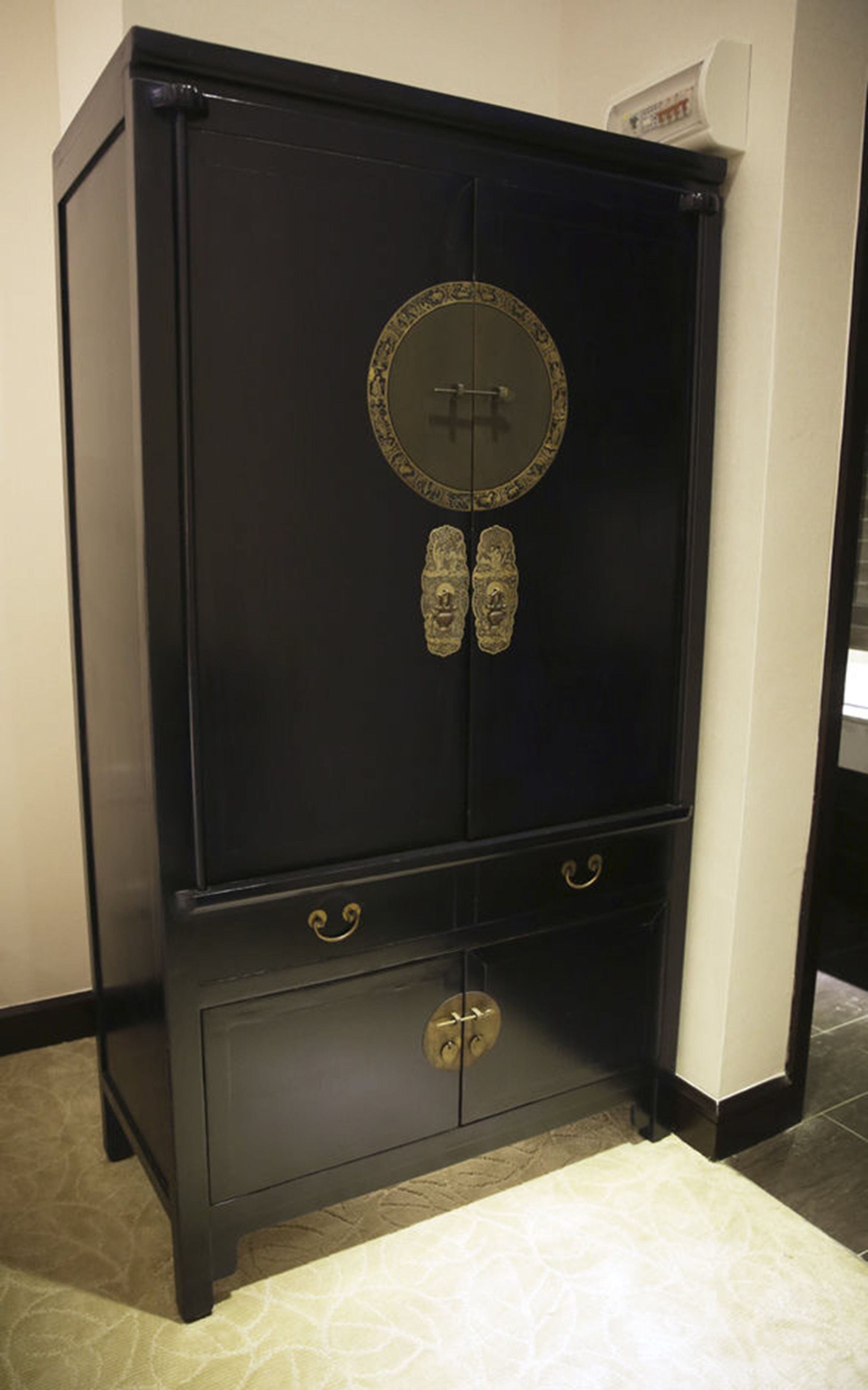 Une armoire noire avec un miroir rond et deux tiroirs.