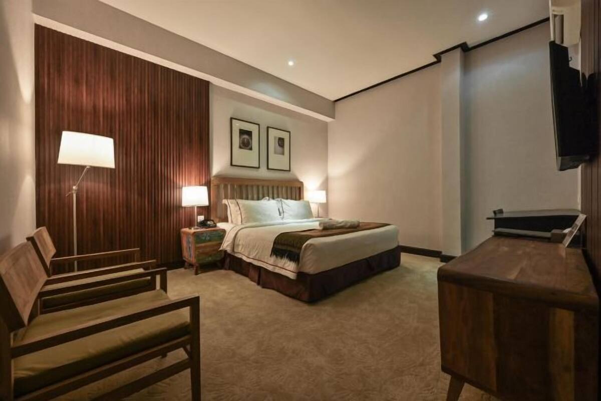 Une chambre d’hôtel avec un lit, des lampes de chevet, un bureau, une chaise et un téléviseur.