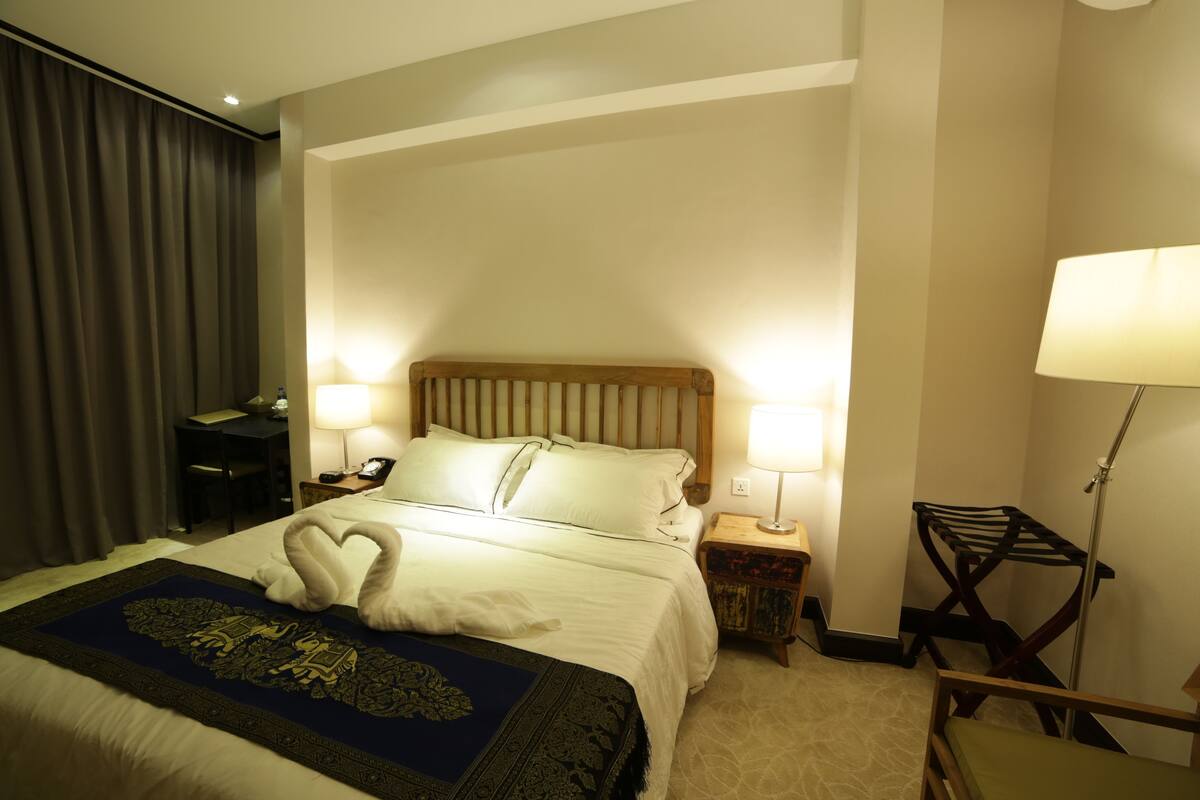 Une chambre d’hôtel avec un grand lit, deux lampes de chevet, un bureau et une chaise.