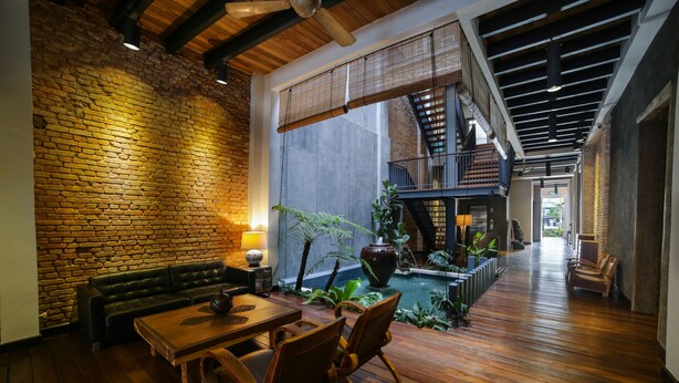 A spacious indoor area with a wooden floor, a brick wall, and a seating area with a table and chairs.