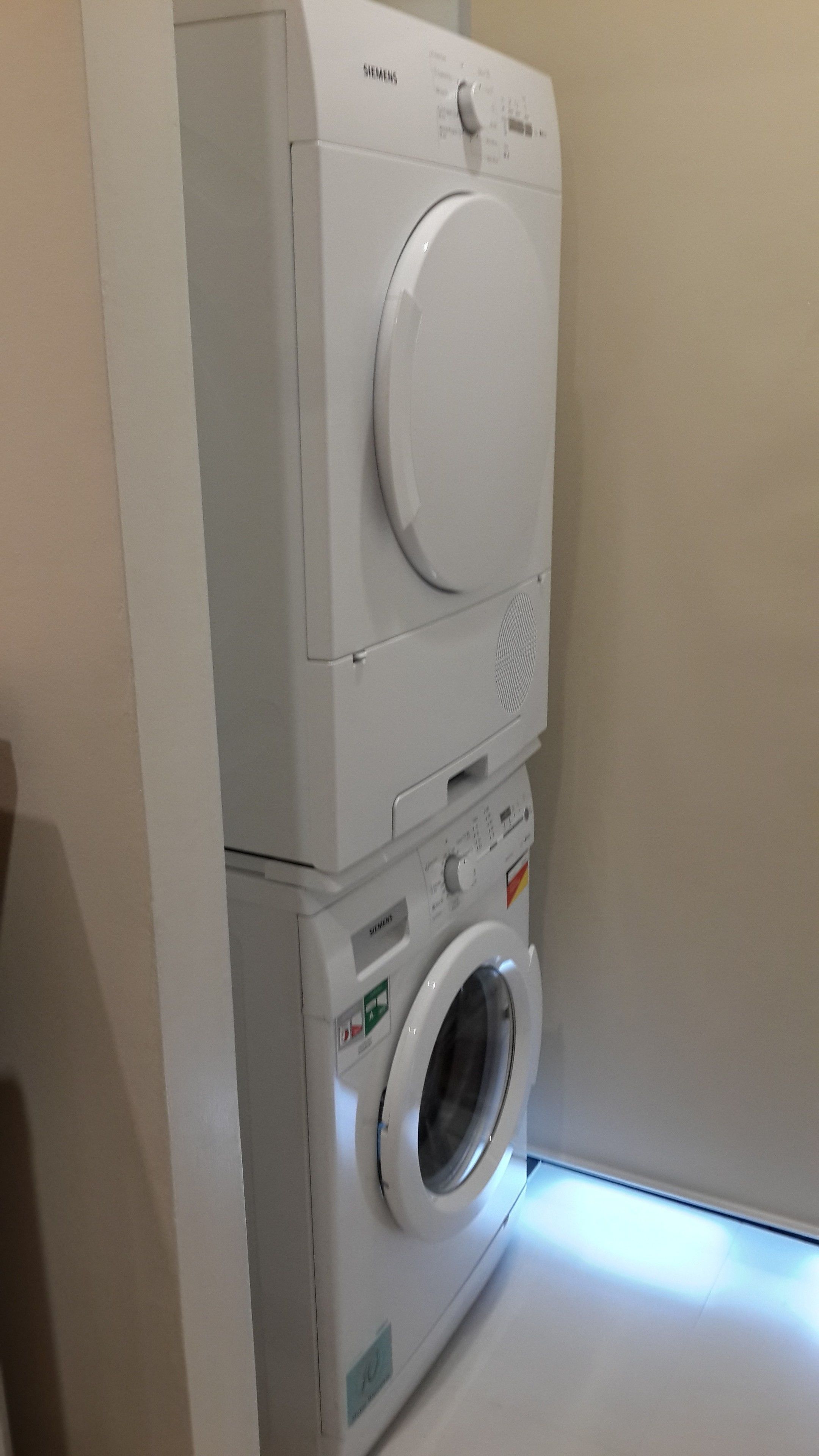 A front-loading white Siemens washing machine in a laundry room.