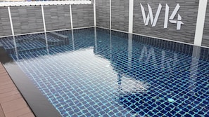 A swimming pool with a geometric tile pattern, a wooden deck, and a wall with a logo. - W14 Pattaya (Pattaya)