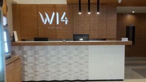 A reception desk with a wooden panel design and a white geometric pattern below. - W14 Pattaya (Pattaya)