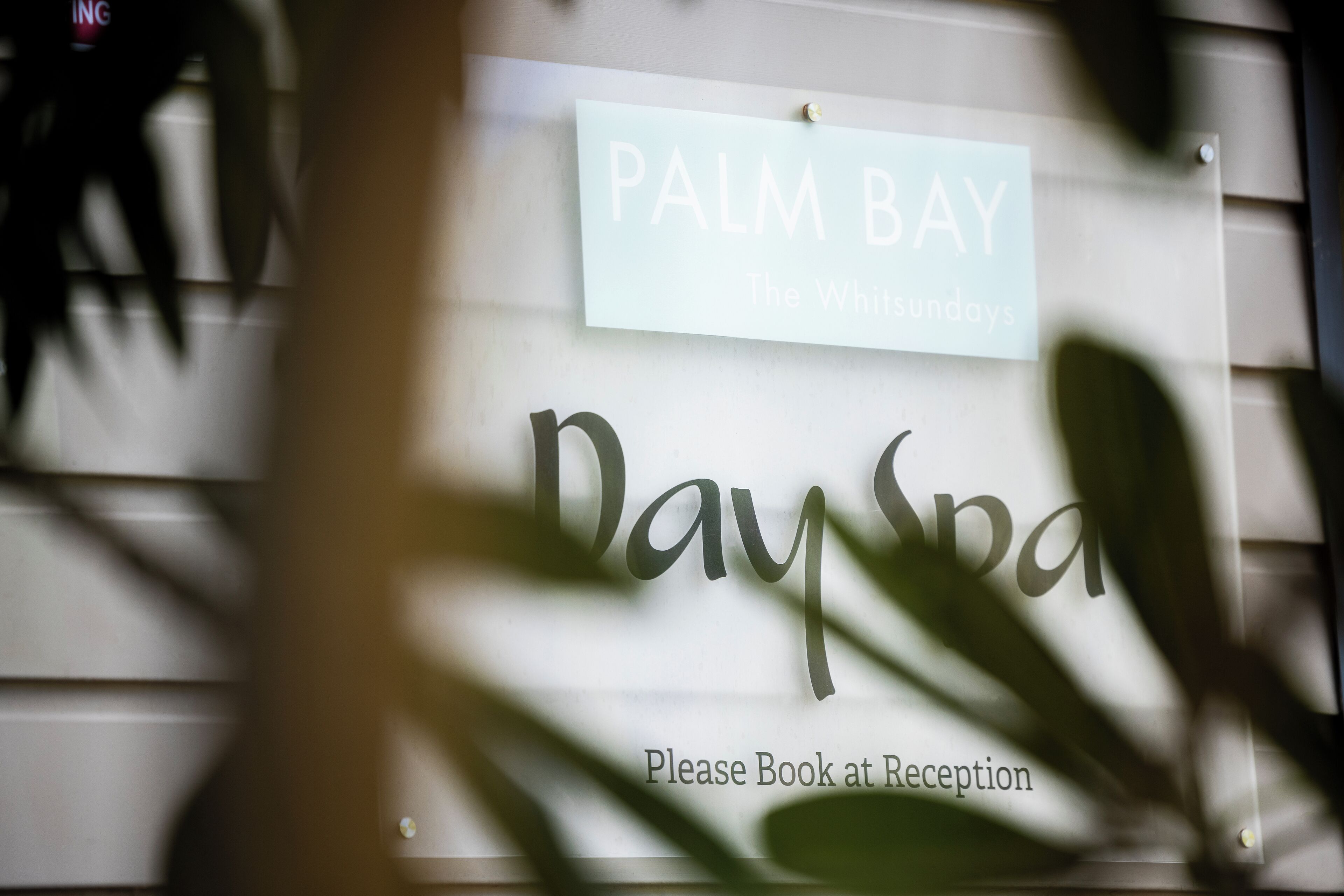A sign for Palm Bay The Whitsundays with a booking instruction.