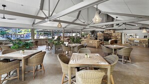 Un'ampia sala da pranzo interna con soffitti alti, mobili in vimini e un camino in pietra.