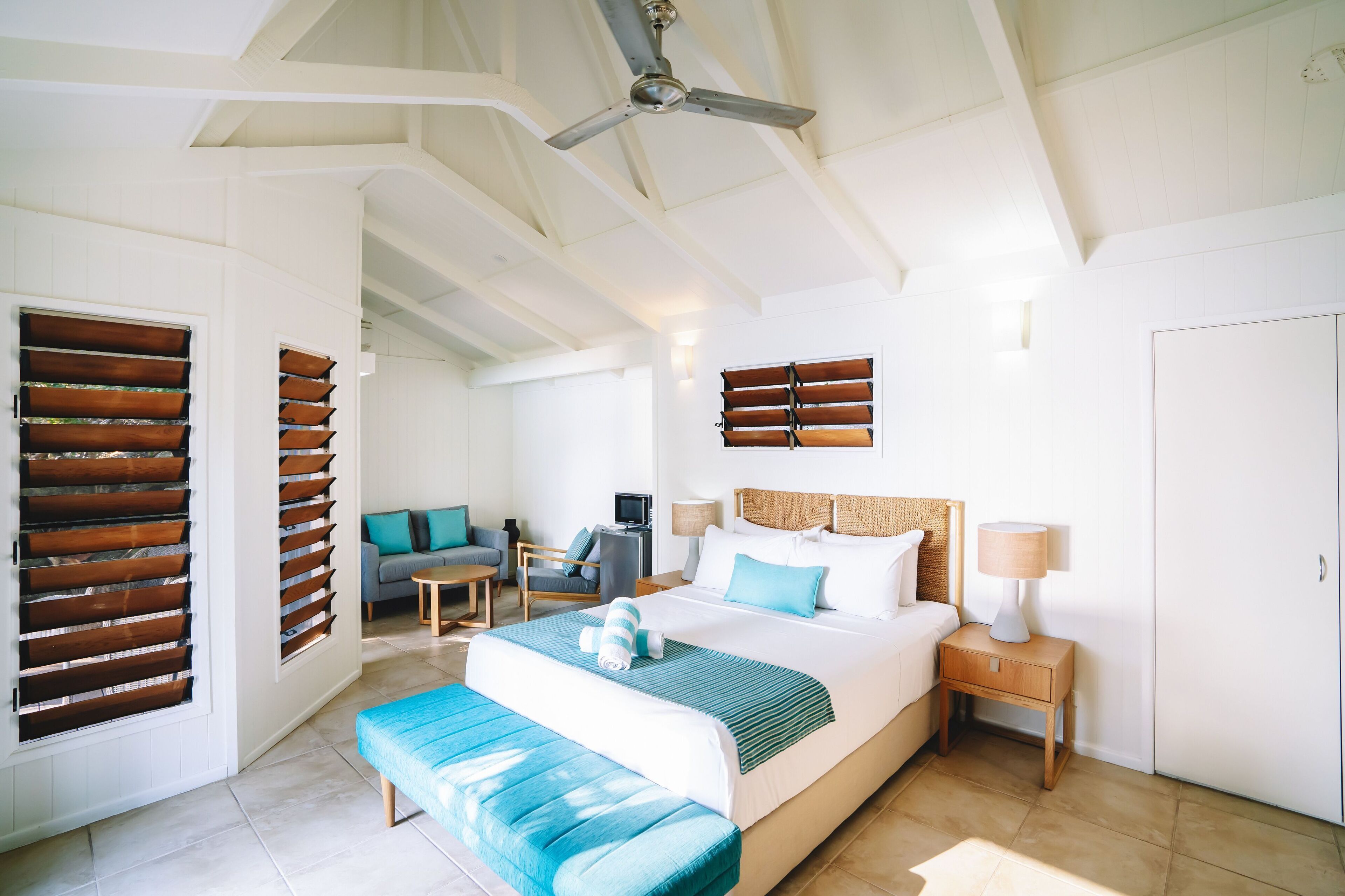A spacious bedroom with a large bed, a ceiling fan, and a view of the outdoors.