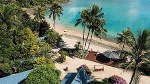 Una località balneare tropicale con una spiaggia sabbiosa, palme e un mare cristallino.