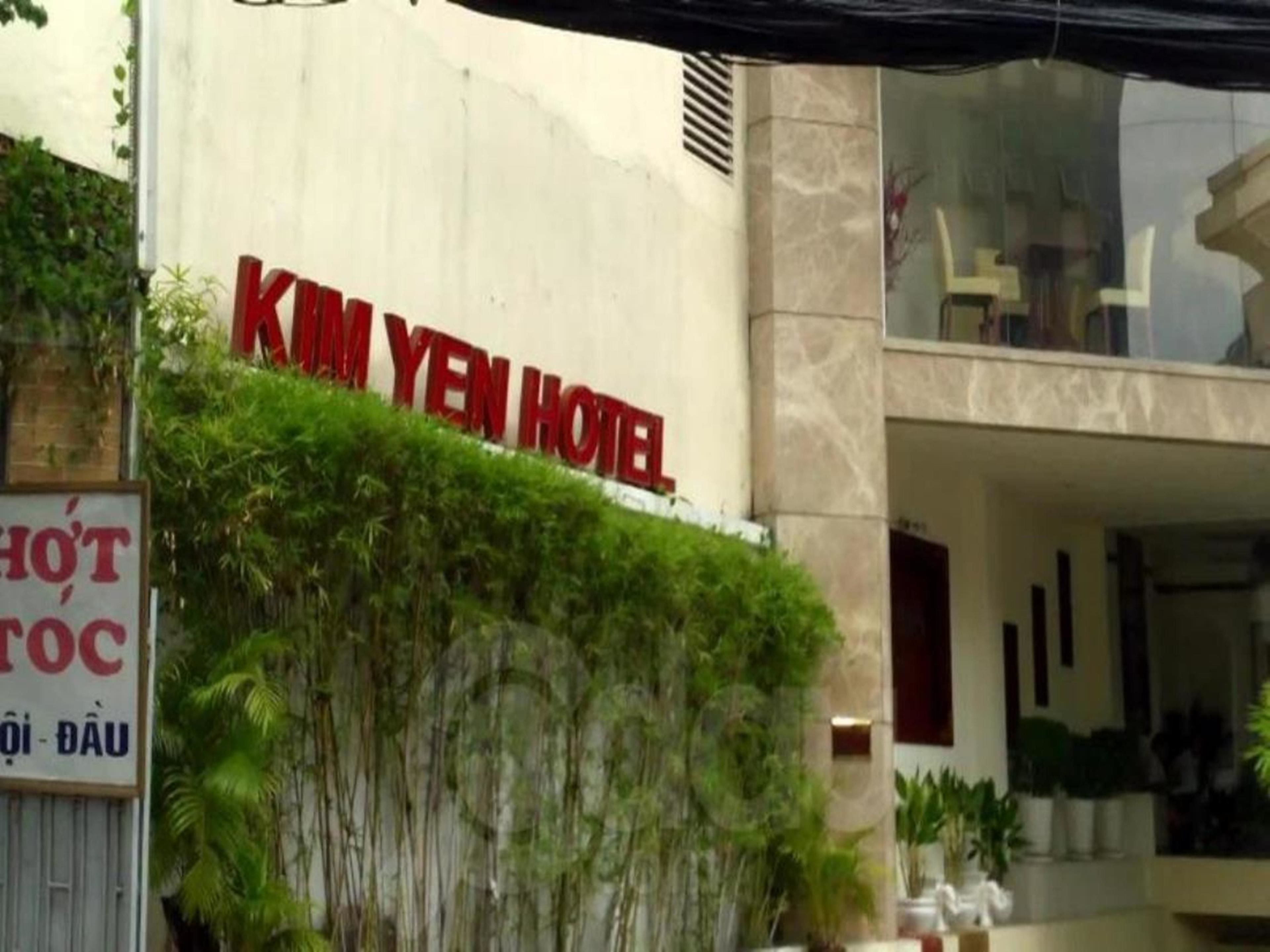Fasaden på Kim Yen Hotel med en skylt ovanför ingången och en informationsskylt till vänster.
